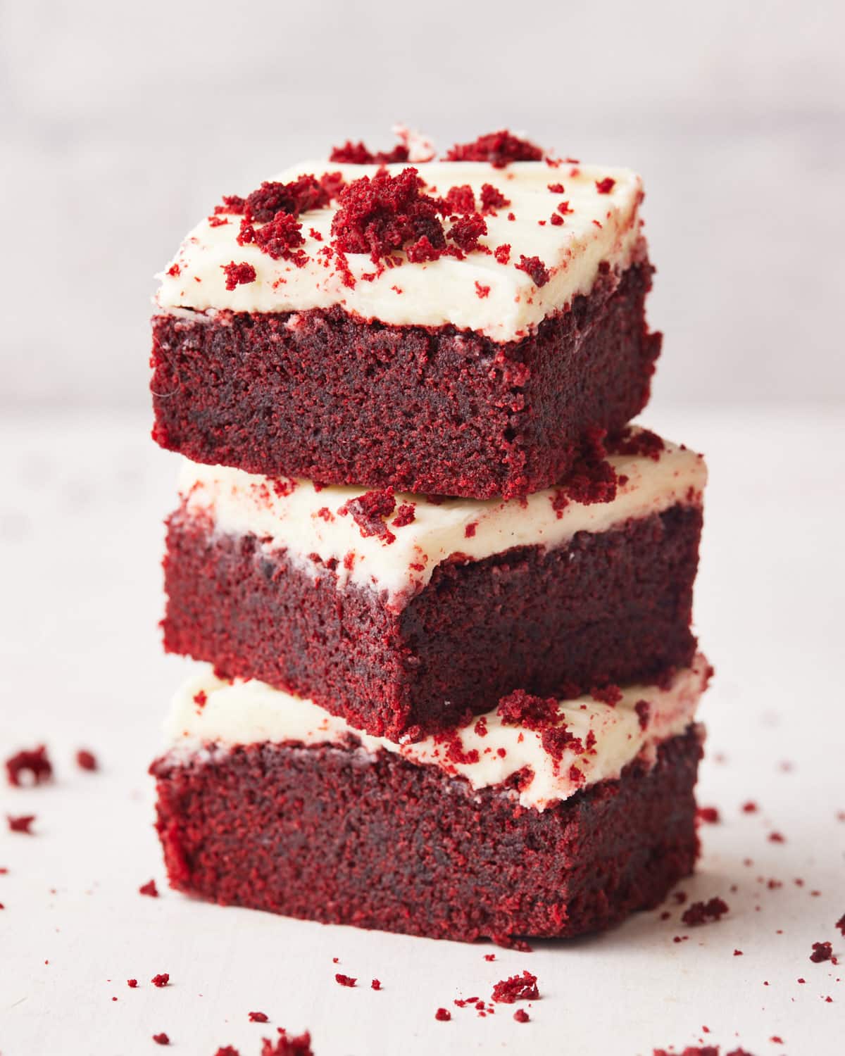 three red velvet brownies on top of each other with cream cheese frosting. 