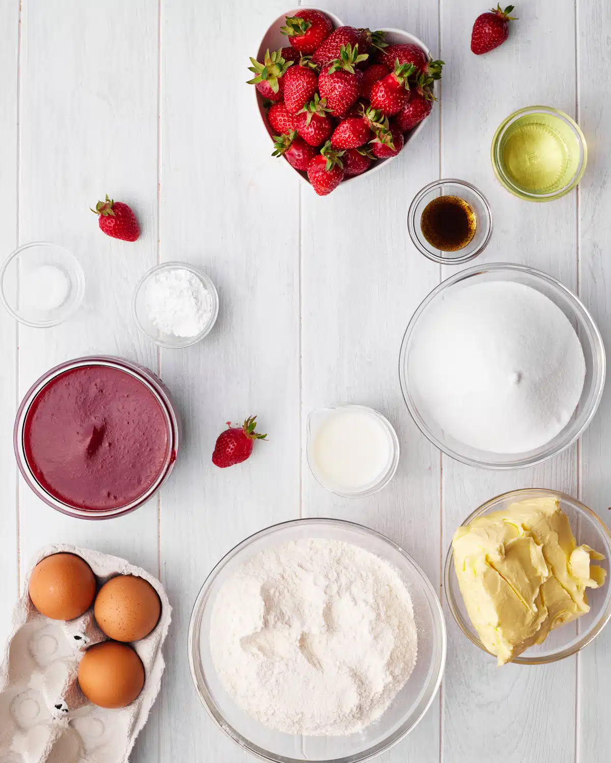 ingredients to make strawberry cupcakes and strawberry filling.  strawberries, strawberry puree, cake flour, butter, sugar, eggs, milk, vegetable oil, vanilla. 