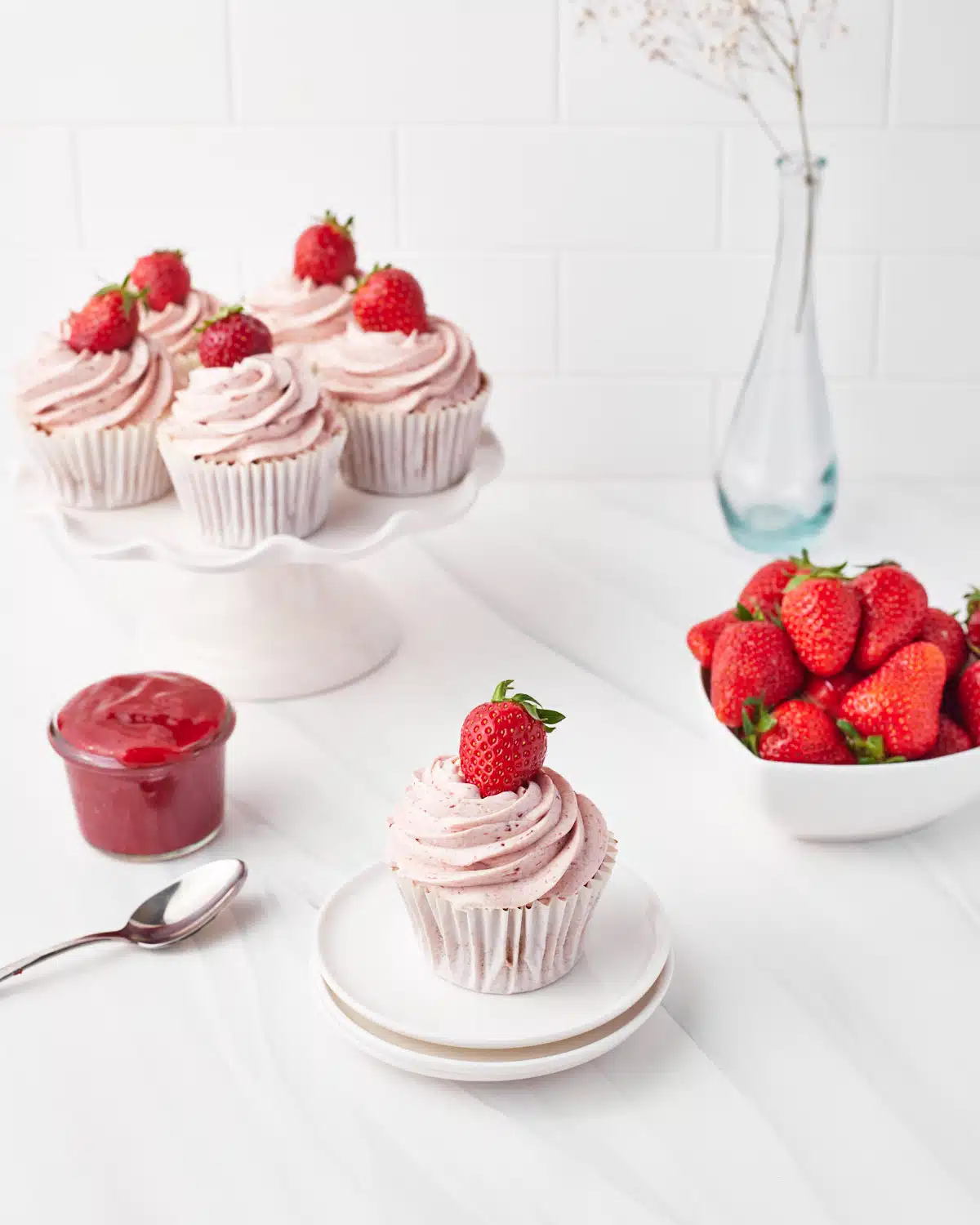 strawberry cupcake on a plate with strawberry frosting and strawberry filling. 