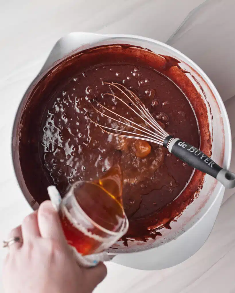pouring hot water and espresso powder into cake batter to make tuxedo cake.