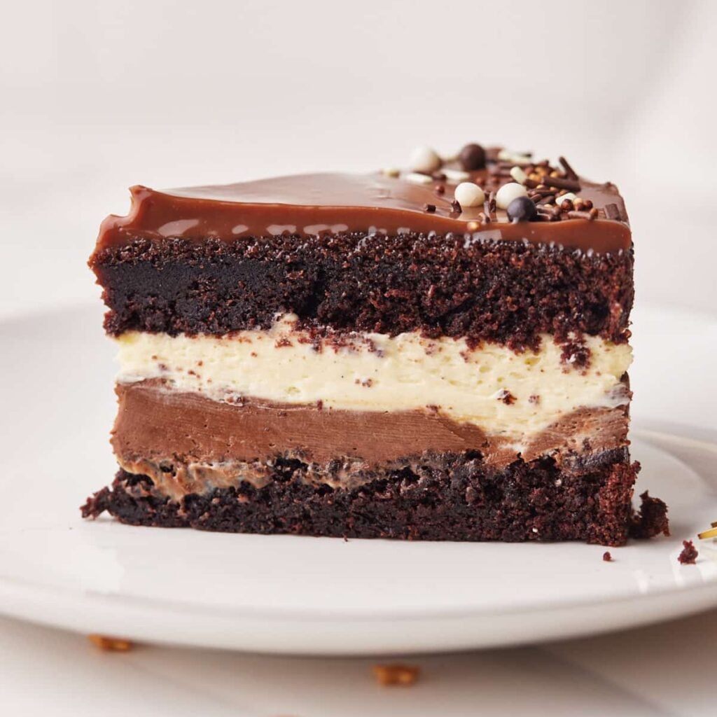 Slice of homemade tuxedo cake showing the layers of chocolate cake, dark chocolate mousse, white chocolate mousse, and ganache.