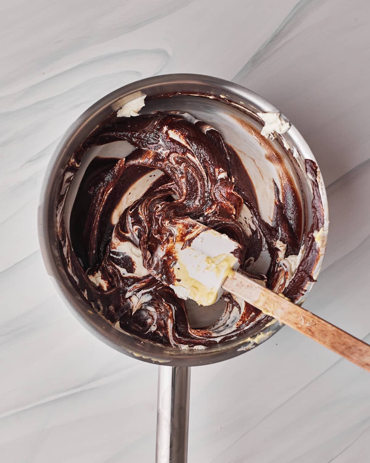 Folding whipped cream into dark chocolate mousse for tuxedo cake.