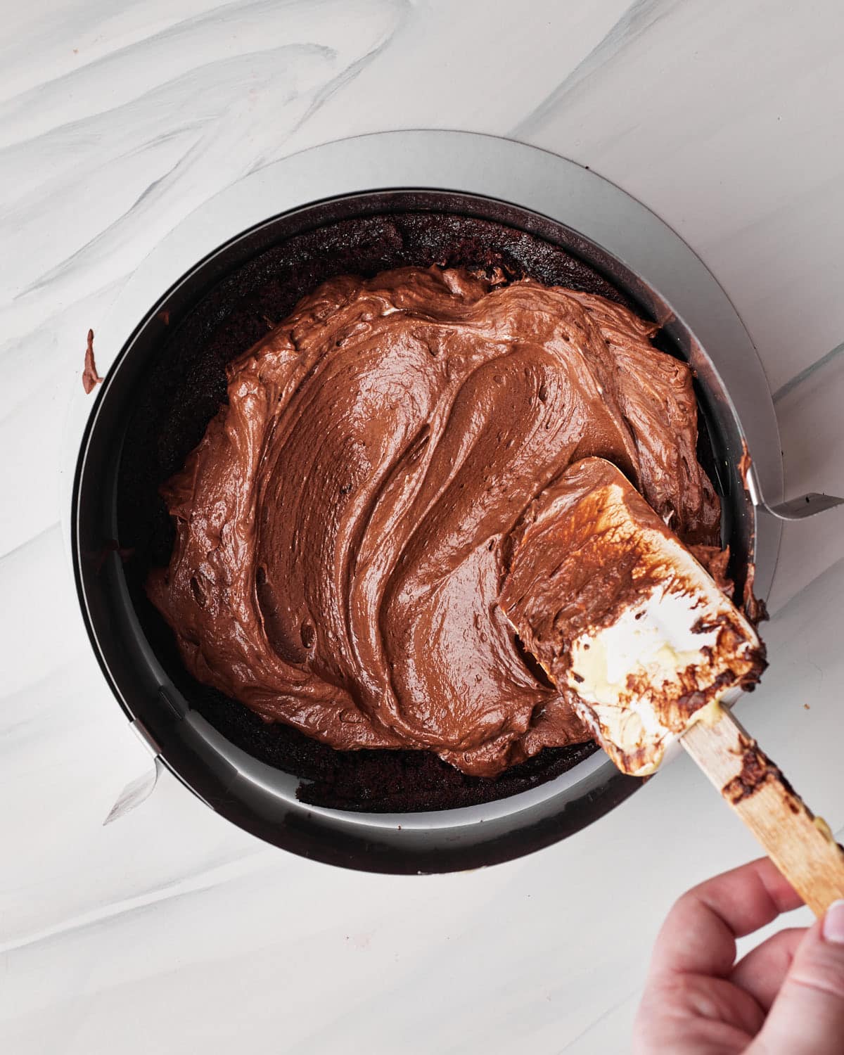 process shot of building the layers of tuxedo cake. chocolate mousse going on top of chocolate cake layer.