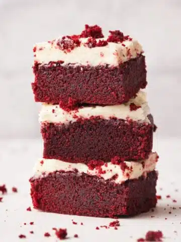 three red velvet brownies stacked on top of each other with cream cheese frosting.