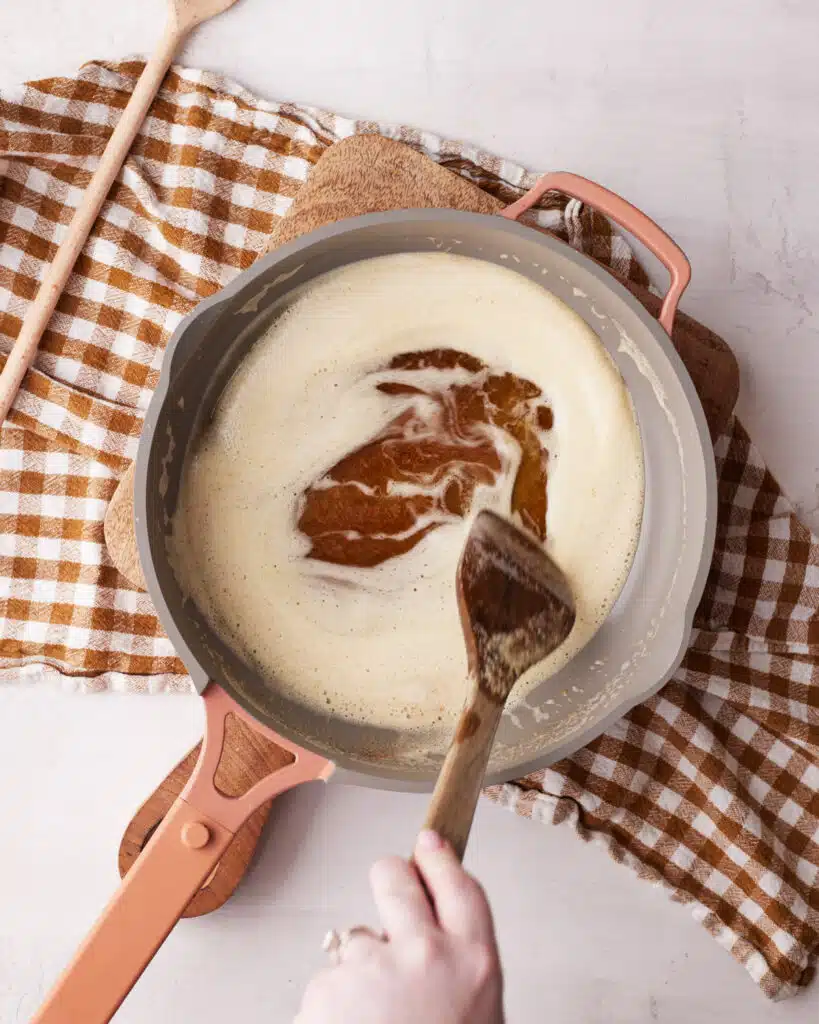 Using a wooden spoon to move foam to the side to check on the color of brown butter.