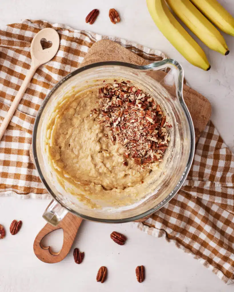 Adding pecans to brown butter banana bread batter.