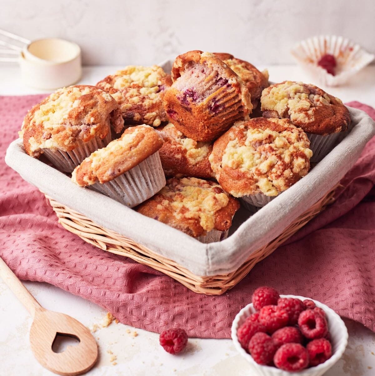 Basket full of freshly baked raspberry muffins with streusel topping.