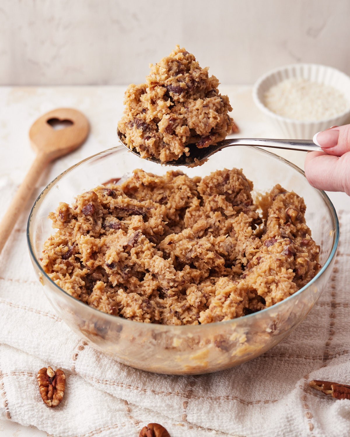 Bowl full of german chocolate frosting with a big spoonful being scooped out. 