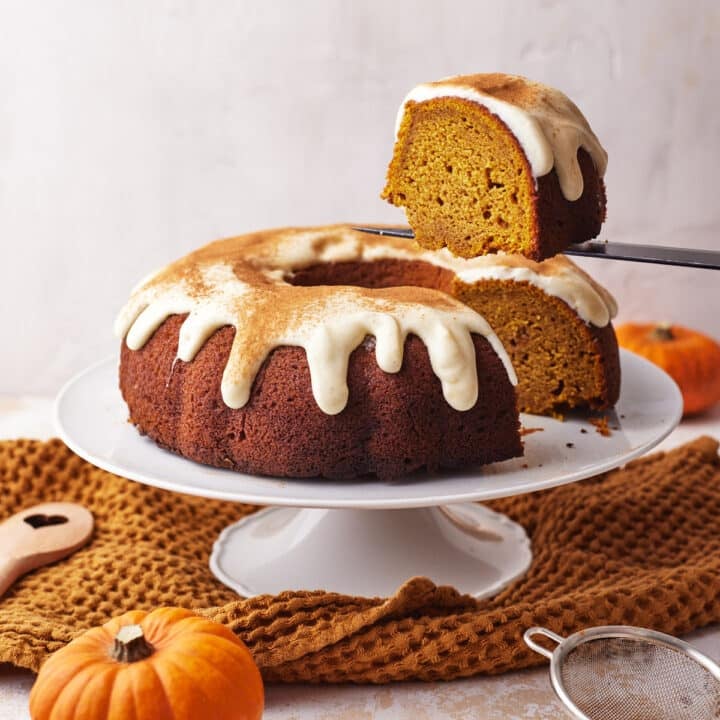 pumpkin bundt cake with cream cheese glaze with a slice being cut out of it.