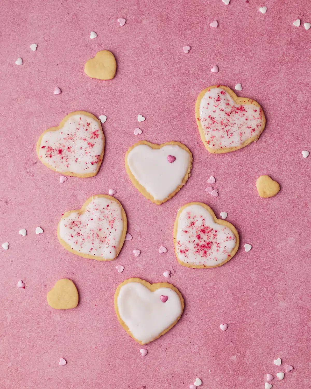heart shaped sugar cookies decorated with simple icing and valentines sprinkles. 