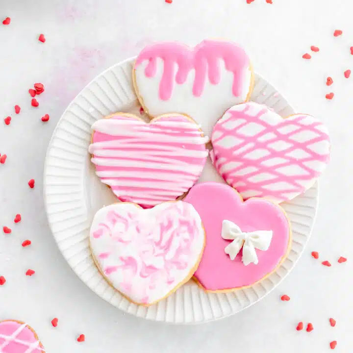 Pink and white decorated heart cookies on a plate.