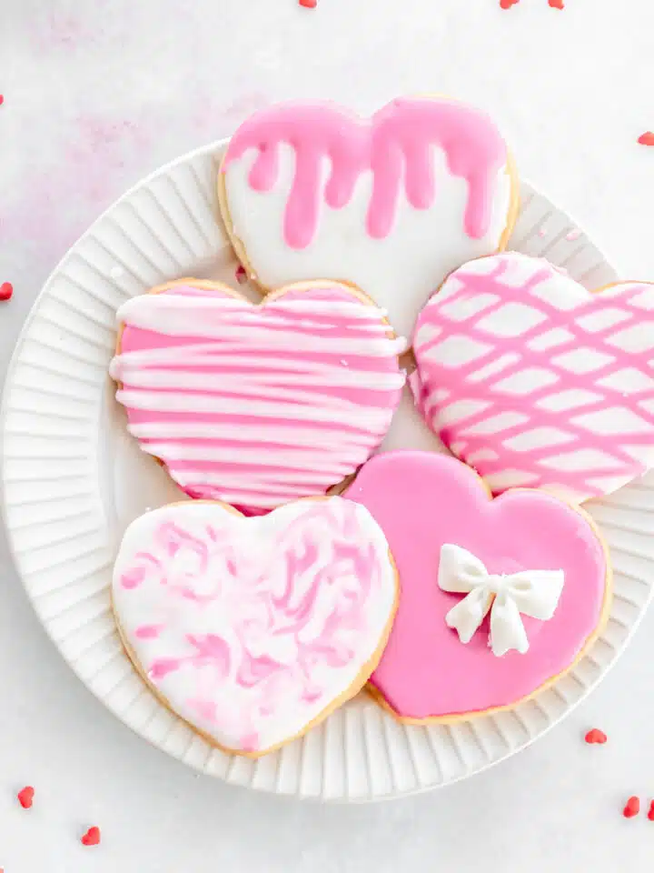 Pink and white decorated heart cookies on a plate.