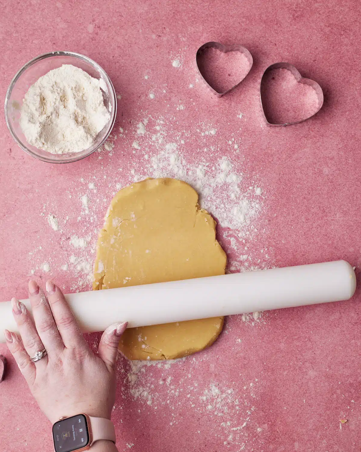Rolling out cookie dough to make heart cookies.