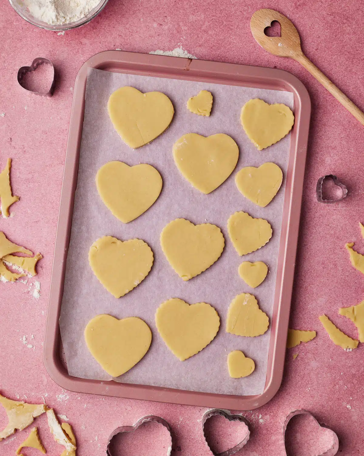 Cut out heart cookies on a baking sheet ready to be baked.