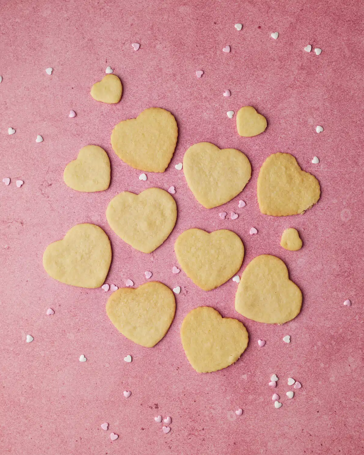 Baked heart cookies on a pink background.