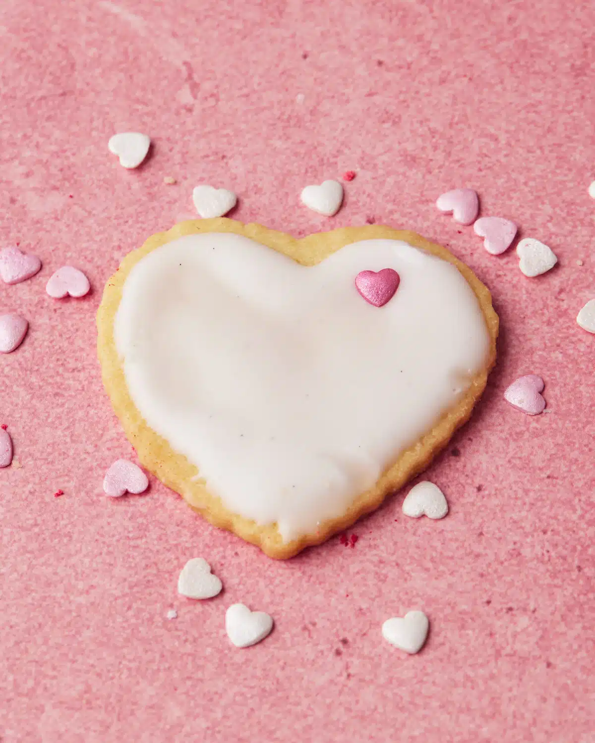 Single heart cookie decorated with heart sprinkles. 