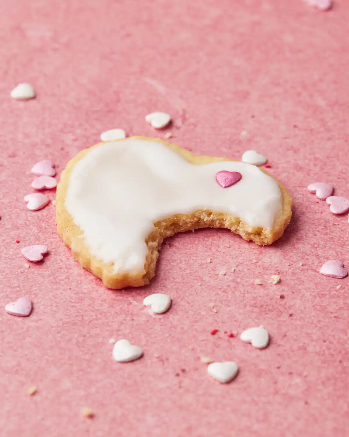 Heart shaped sugar cookie with a bite taken out of it.