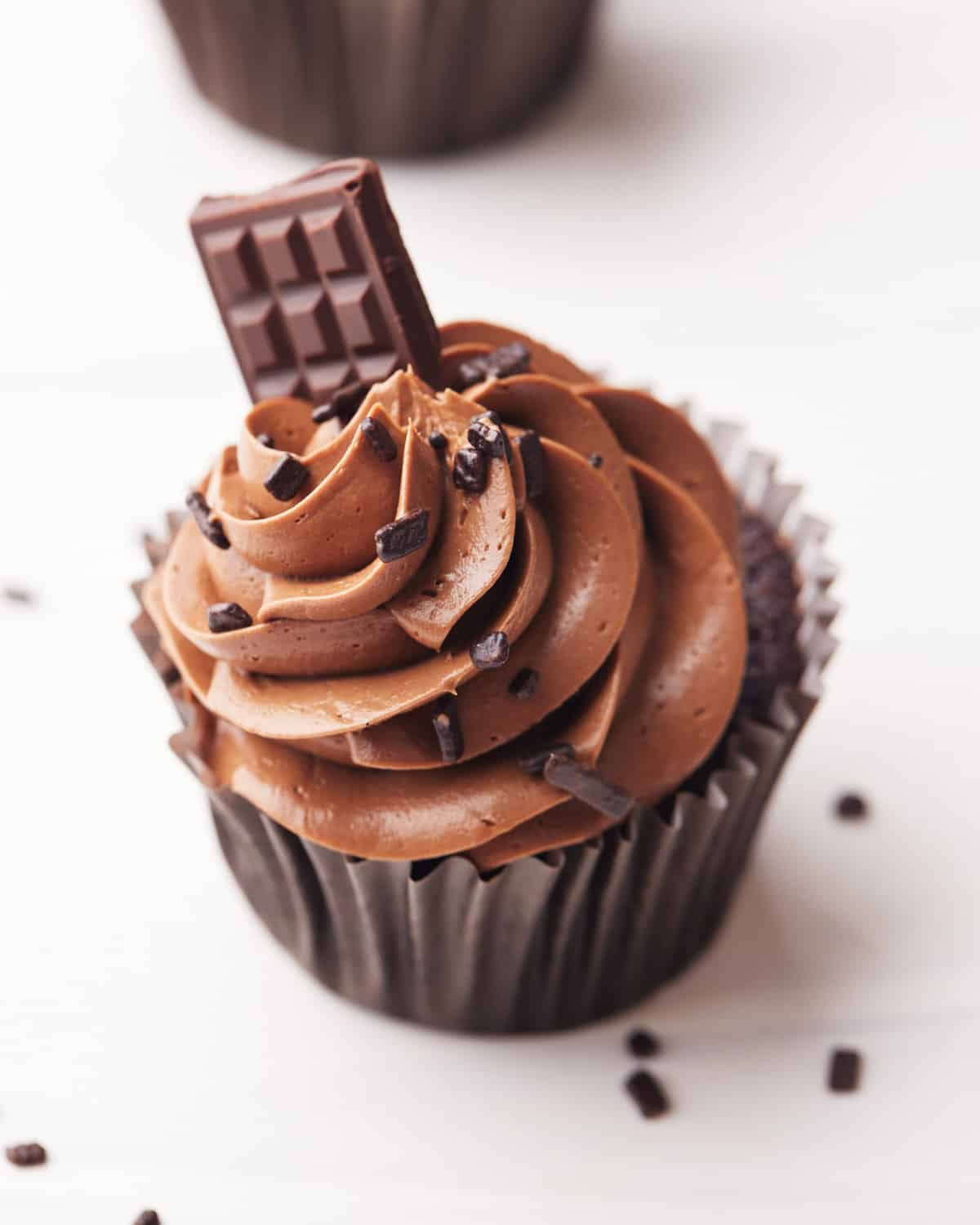Top down view of a chocolate cupcake with chocolate buttercream piped in a swirl on top and a mini chocolate bar sticking out the top.