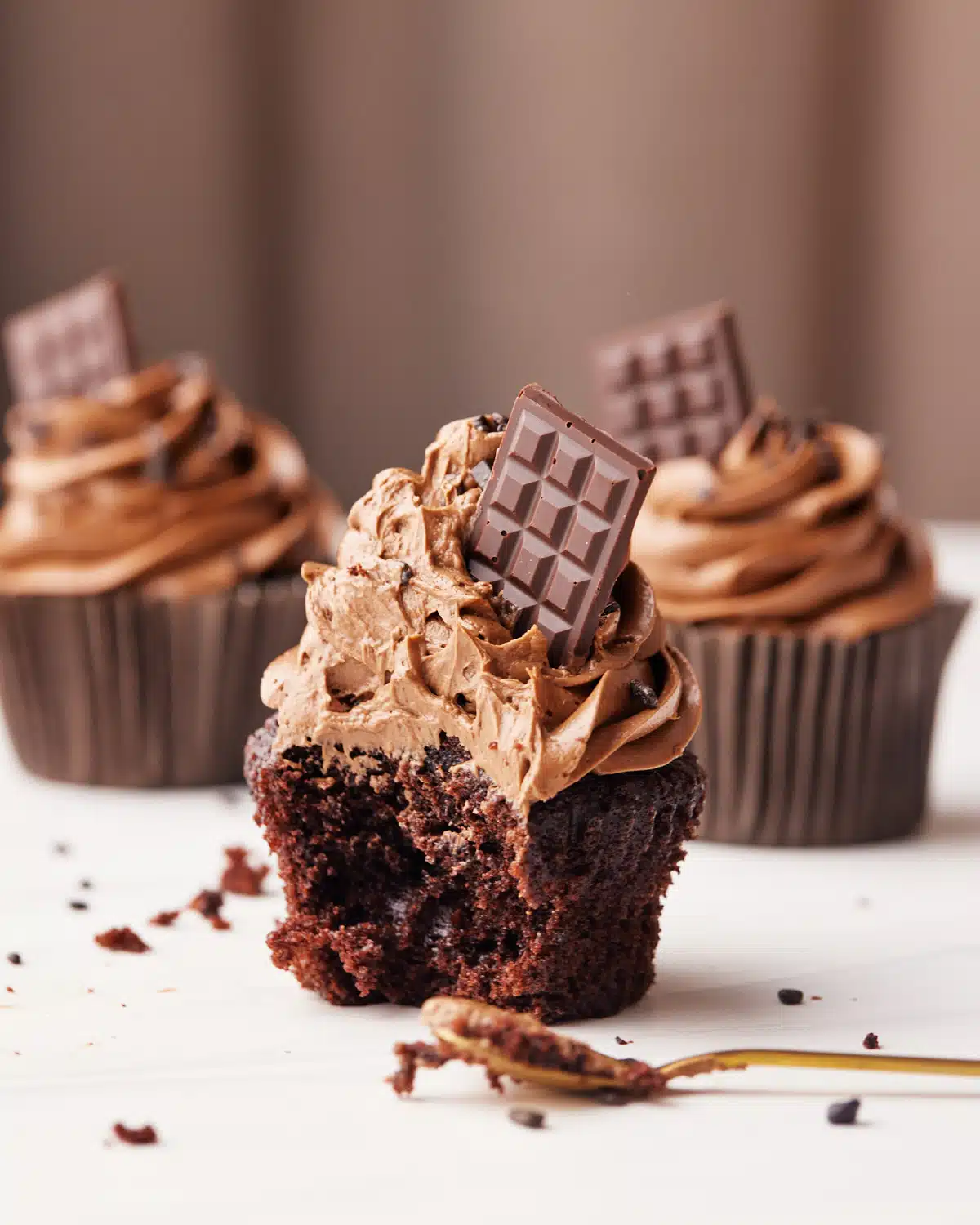 Chocolate cupcake with a bite taken out of it to show silky smooth chocolate buttercream.