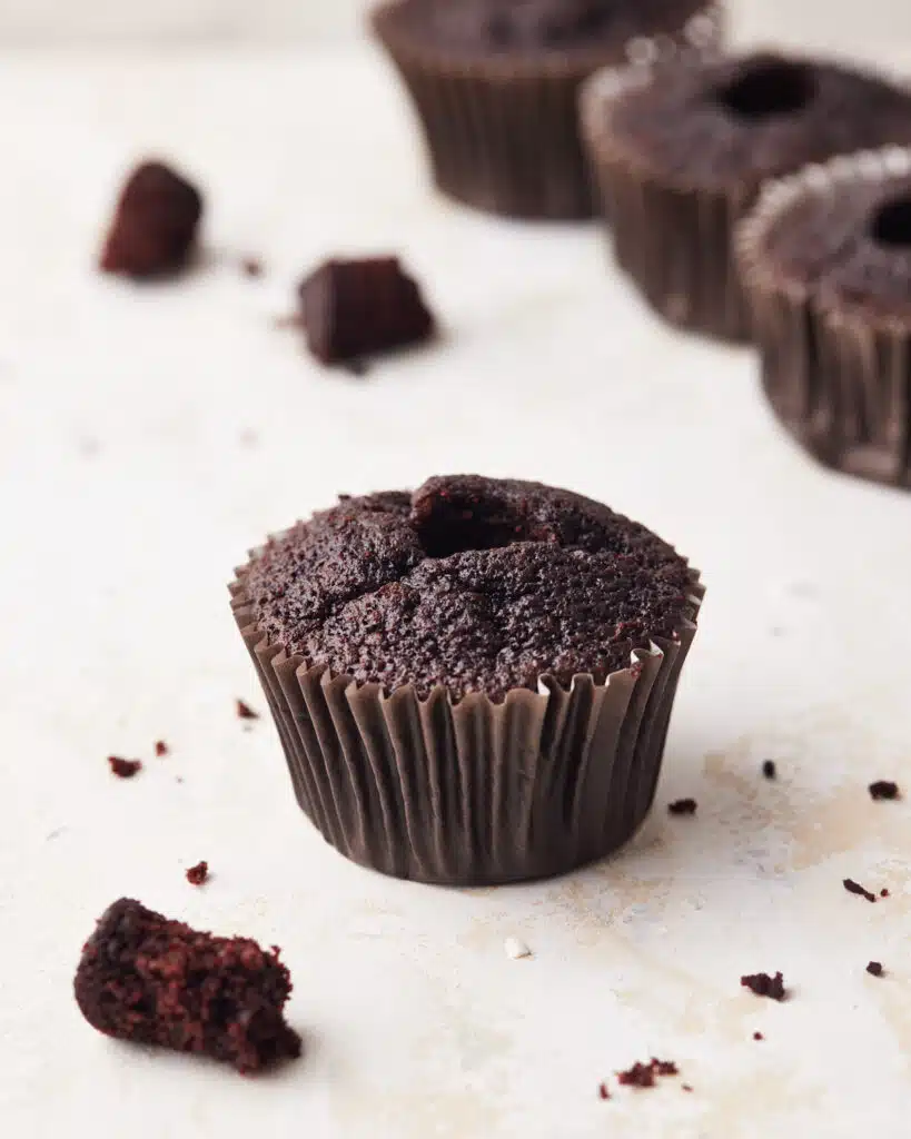 Chocolate cupcake with the center cored out, ready to be filled with chocolate ganache.
