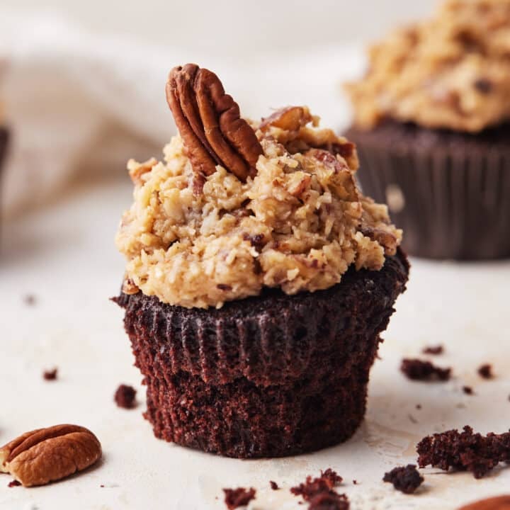 Single german chocolate cupcake with coconut pecan frosting and a single pecan perched on top.