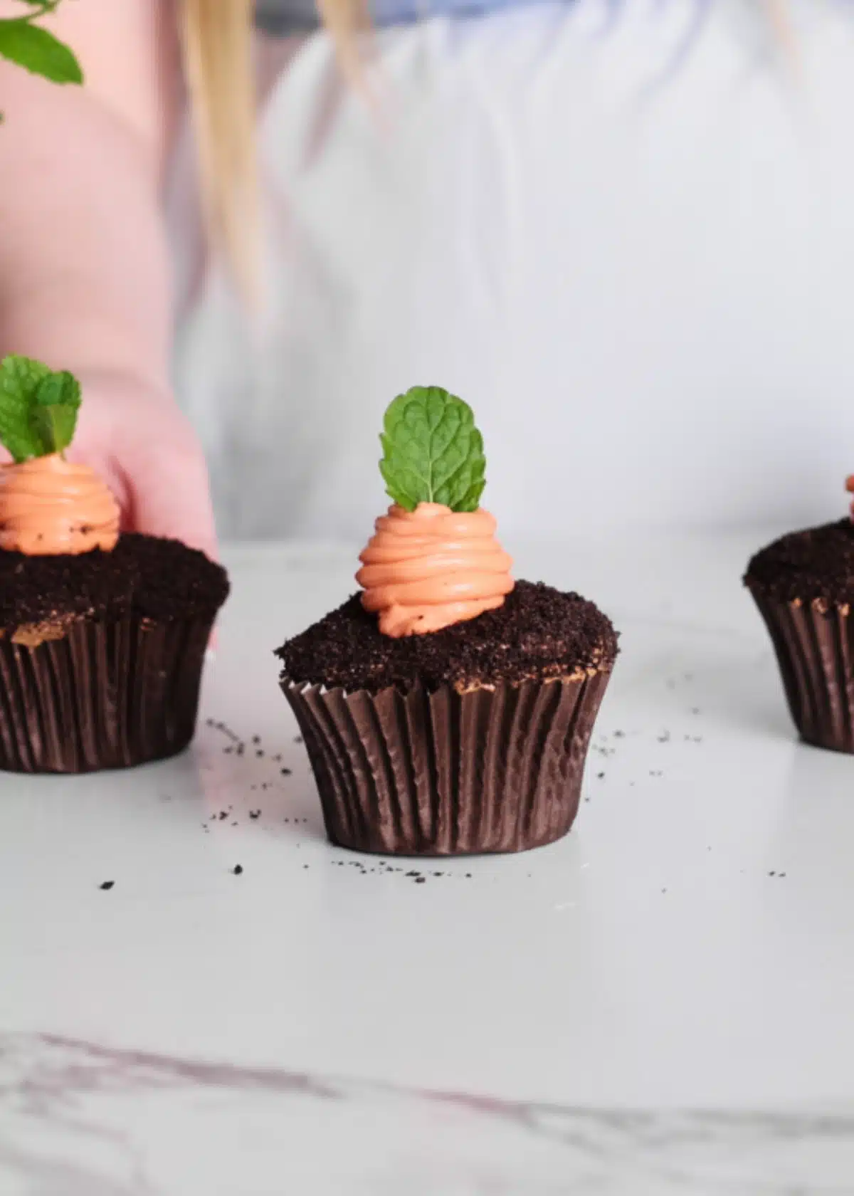 Carrot patch cupcakes - chocolate cupcakes with a piped orange carrot in the middle and a sprig of fresh mint as the leaves. 