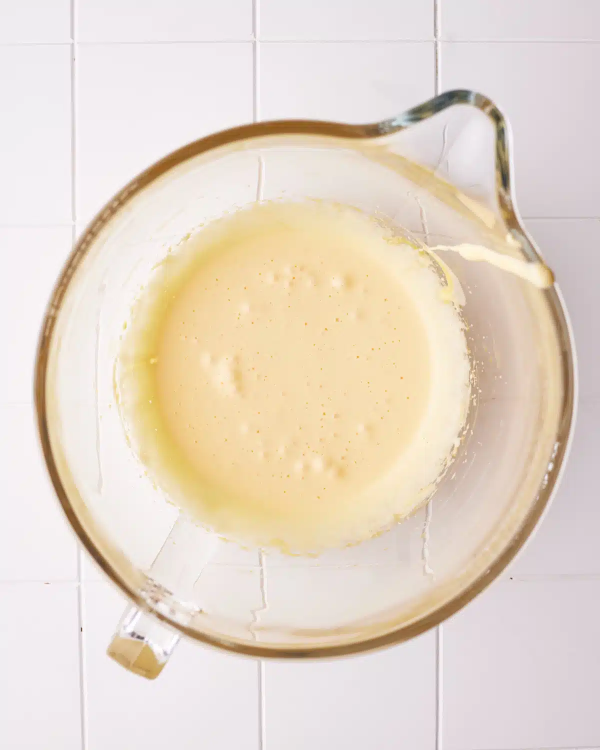 Whipped egg yolks in a glass bowl to make French buttercream.