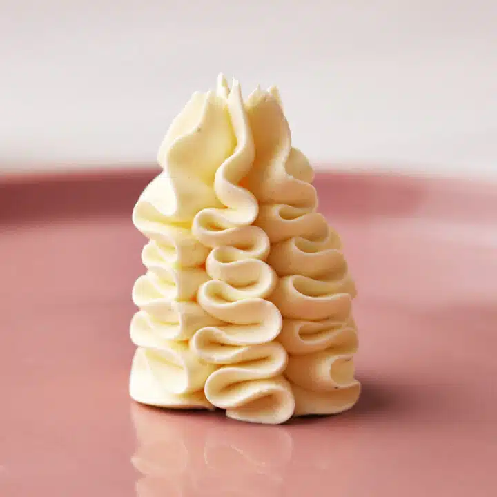 French buttercream piped onto a pink plate.