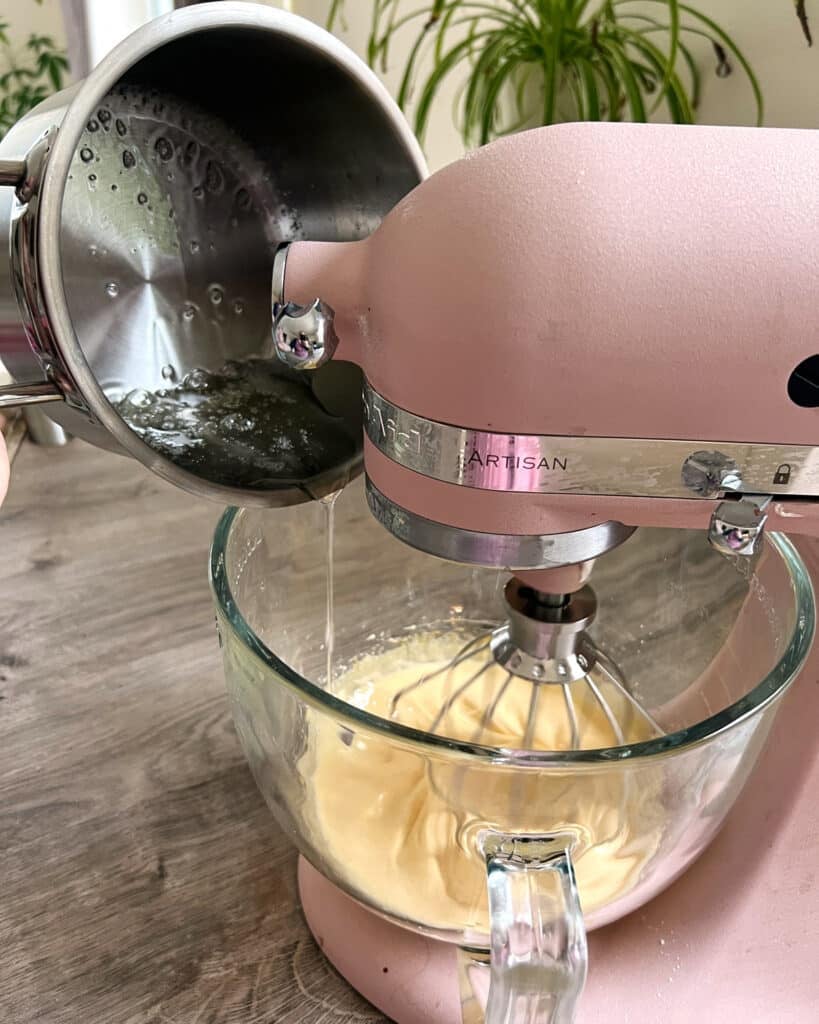 Pouring hot sugar syrup into a stand mixer with whipped egg yolks in it to make French Buttercream.