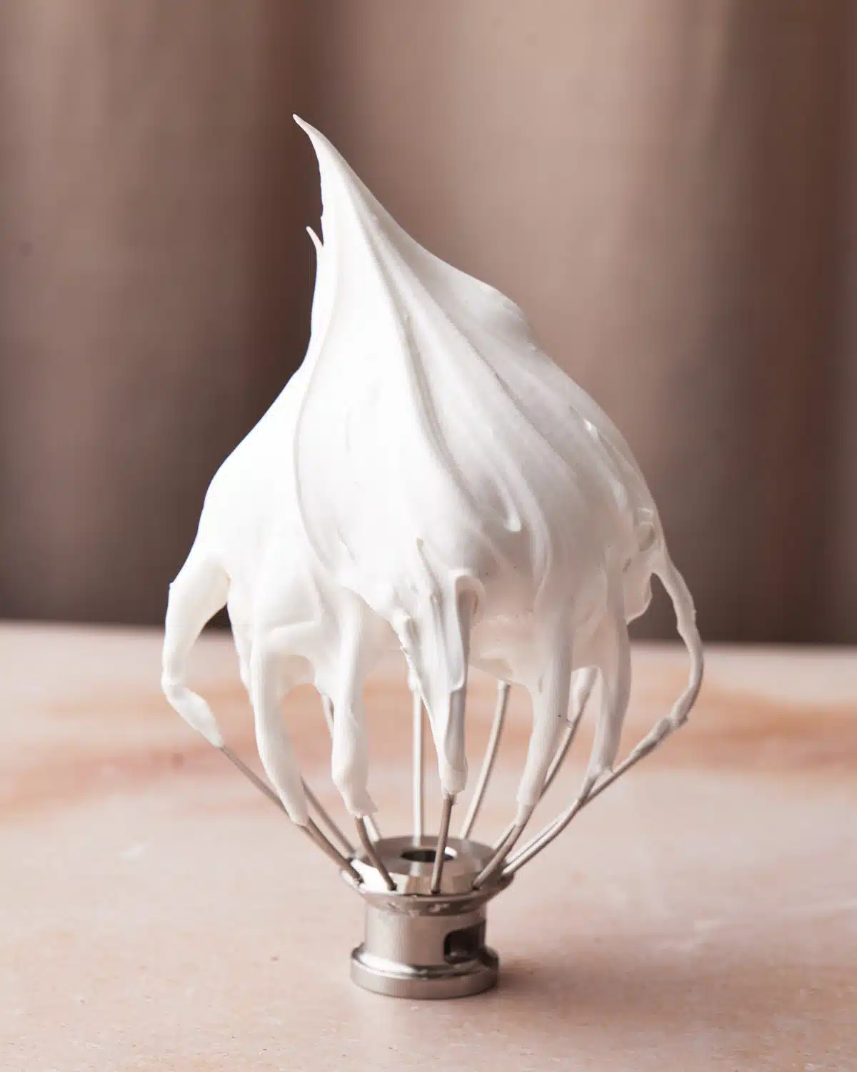 Marshmallow frosting on a stand mixer whisk.