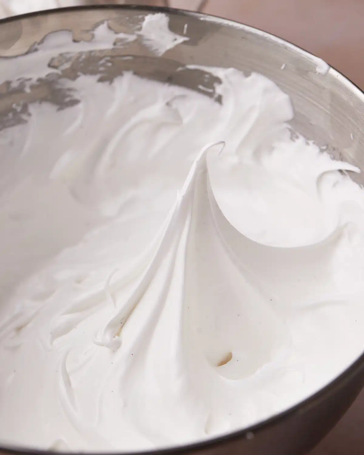Homemade marshmallow frosting in a mixing bowl - glossy with stiff peaks. 