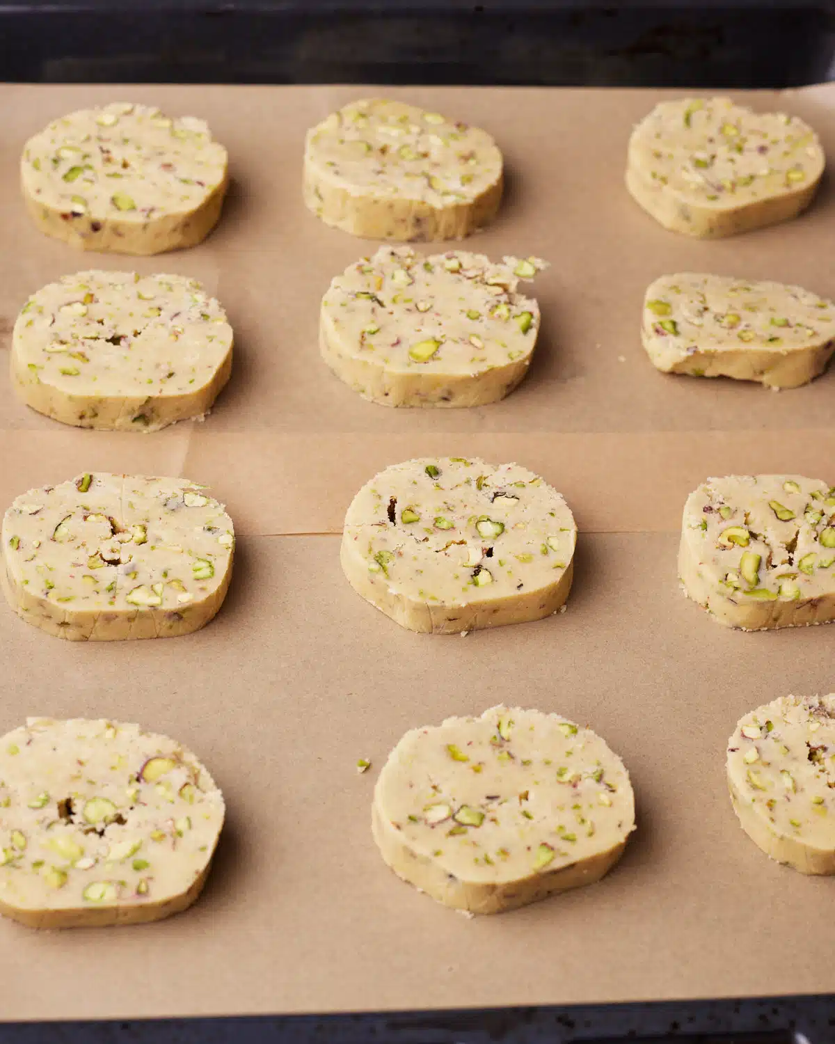 Pistachio shortbreads using the slice and bake method on a baking sheet ready to be baked.