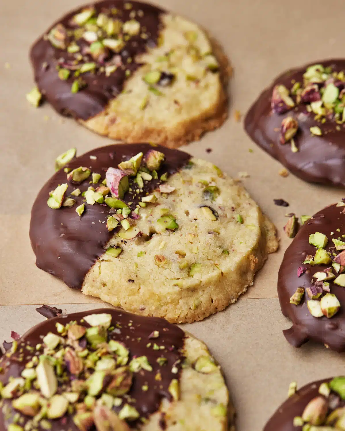 Round pistachio shortbread cookies in a row, dipped in chocolate and topped with chopped pistachios to make the perfect easy desserts!