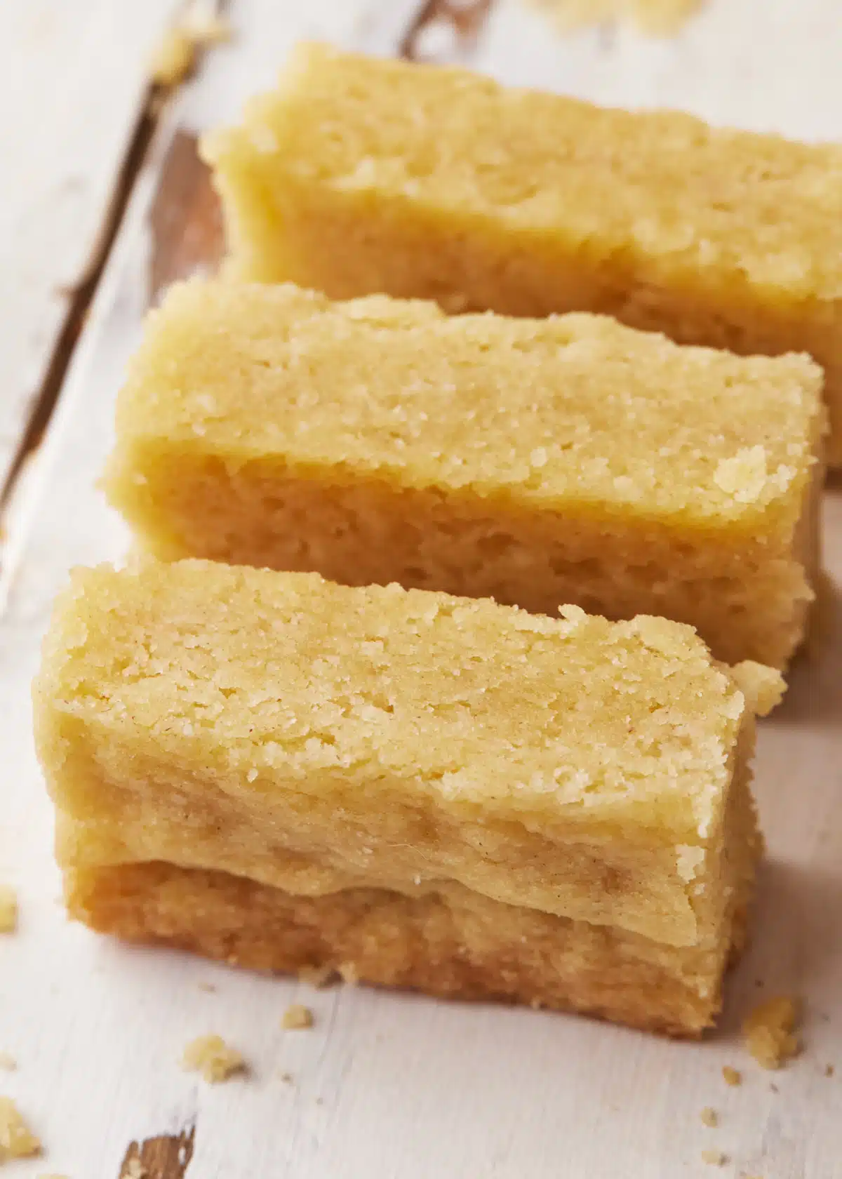 Three fingers of scottish shortbread lying on their side to show soft texture. 