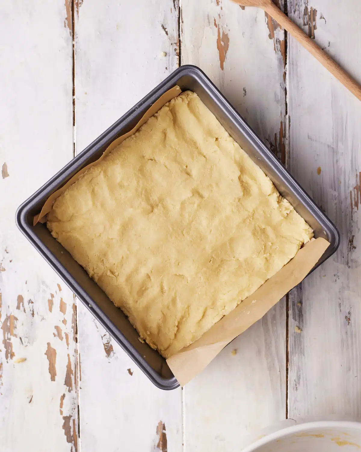 Shortbread dough that has been pressed into a square baking pan.