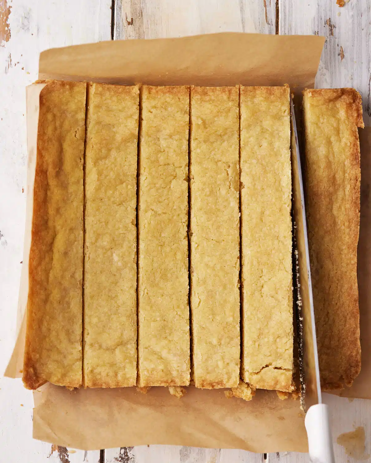 Scottish shortbread being sliced into fingers with a large knife.