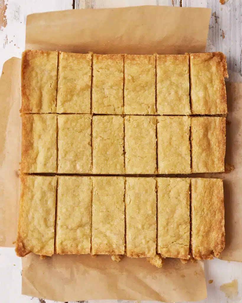 Scottish shortbread being sliced into fingers with a large knife.