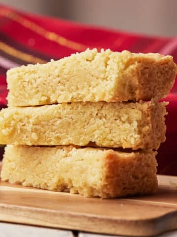 Three fingers of scottish shortbread in a pile showing the soft and crumbly texture.