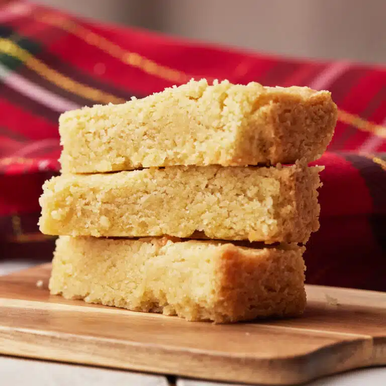 Three fingers of scottish shortbread in a pile showing the soft and crumbly texture.