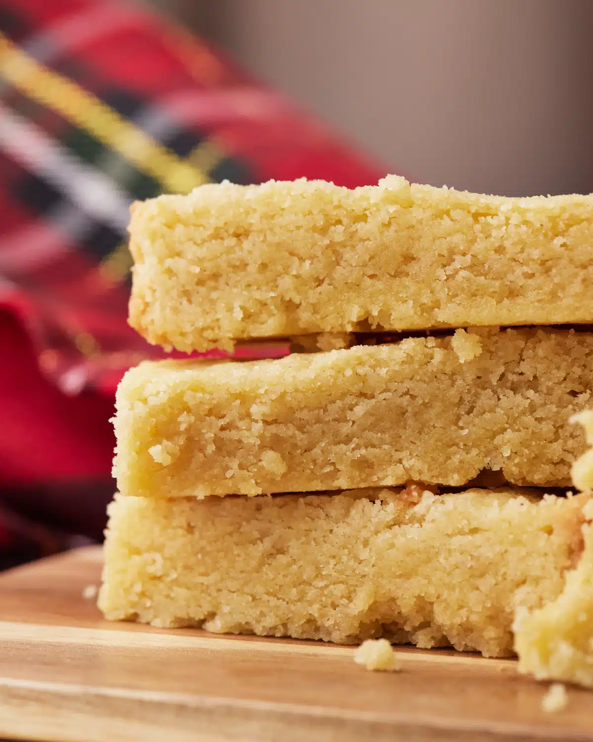 Close up of three fingers of scottish shortbread stacked on top of each other, showing the sides to reveal crumbly texture. 