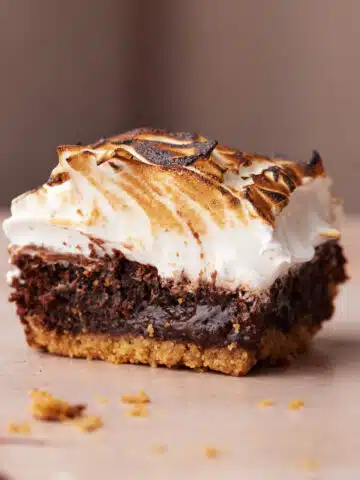 Close up of a single s'mores brownie with graham cracker base and toasted marshmallow frosting.