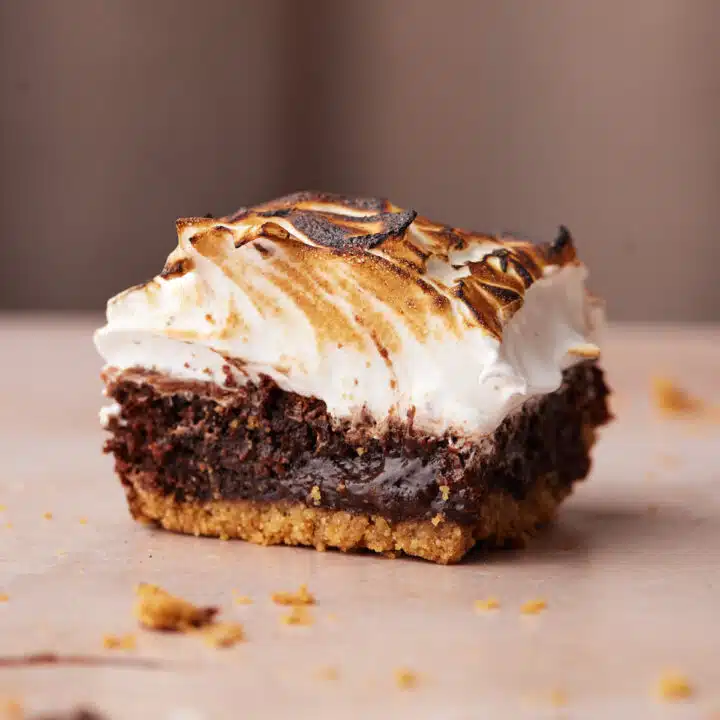 Close up of a single s'mores brownie with graham cracker base and toasted marshmallow frosting.