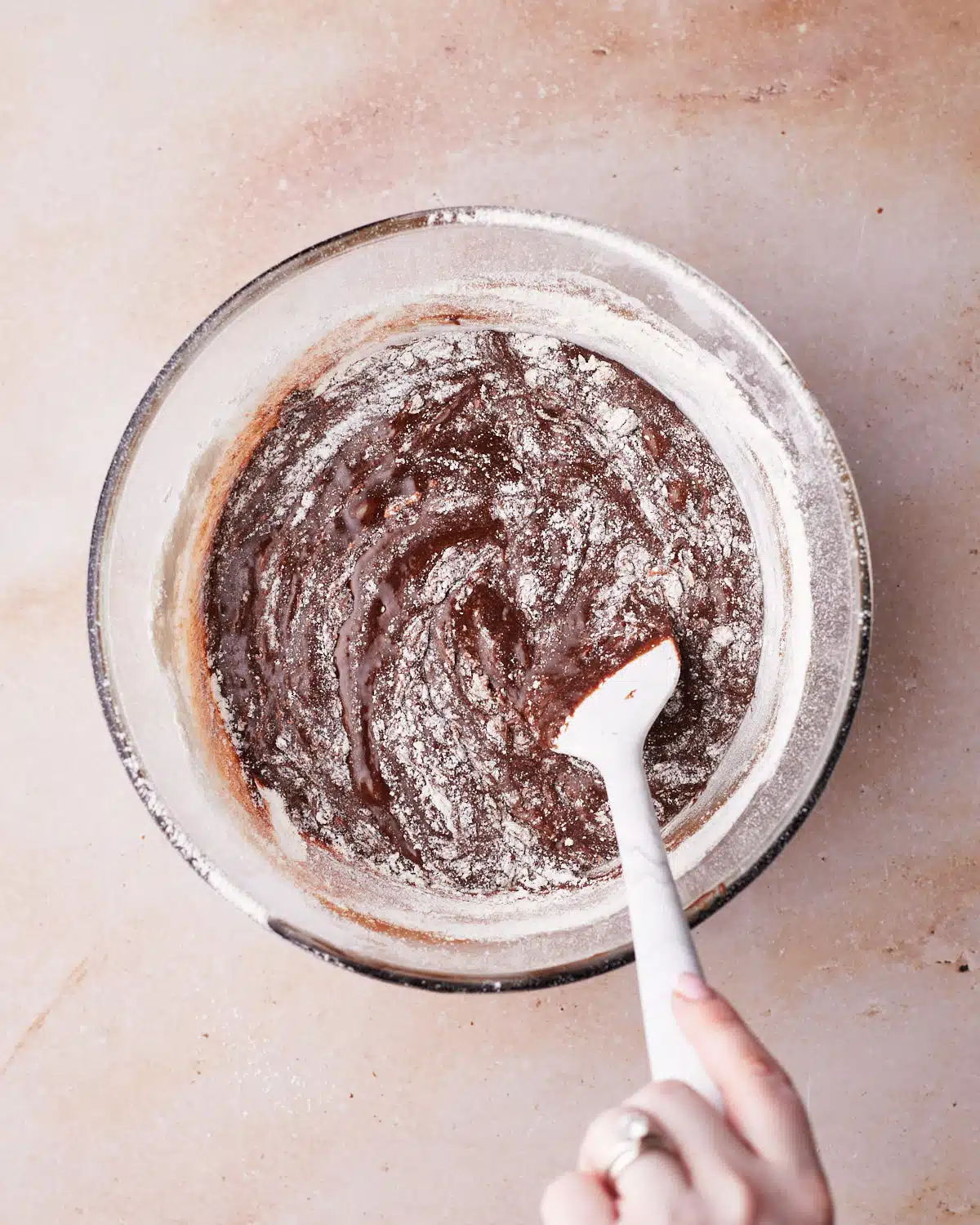 Flour being folded into brownie batter for s'mores brownies.