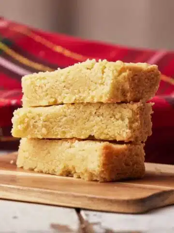 Three fingers of scottish shortbread in a pile showing the soft and crumbly texture.