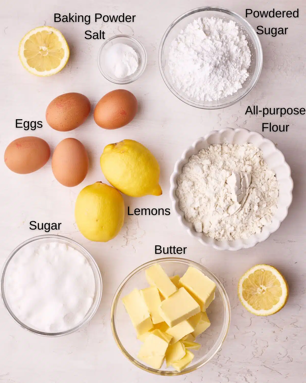 Ingredients to make lemon drizzle cake - butter, sugar, eggs, lemons, flour, baking powder and powdered sugar. 