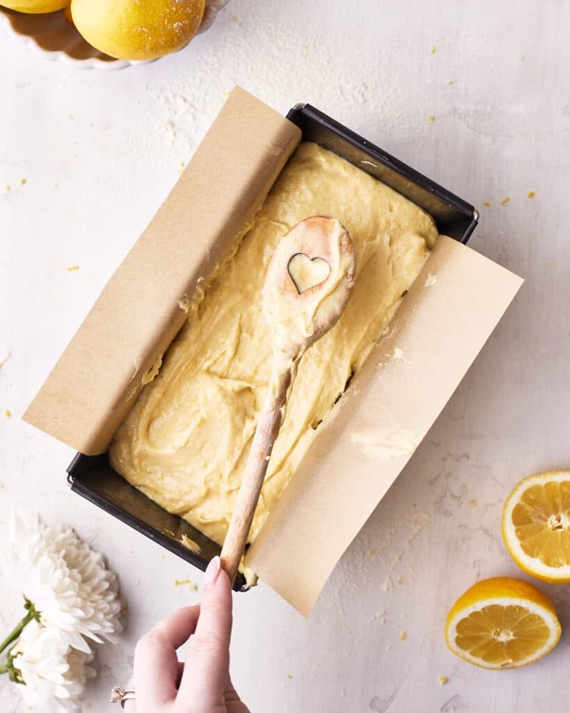 Raw lemon cake batter in a loaf pan to make lemon drizzle cake.