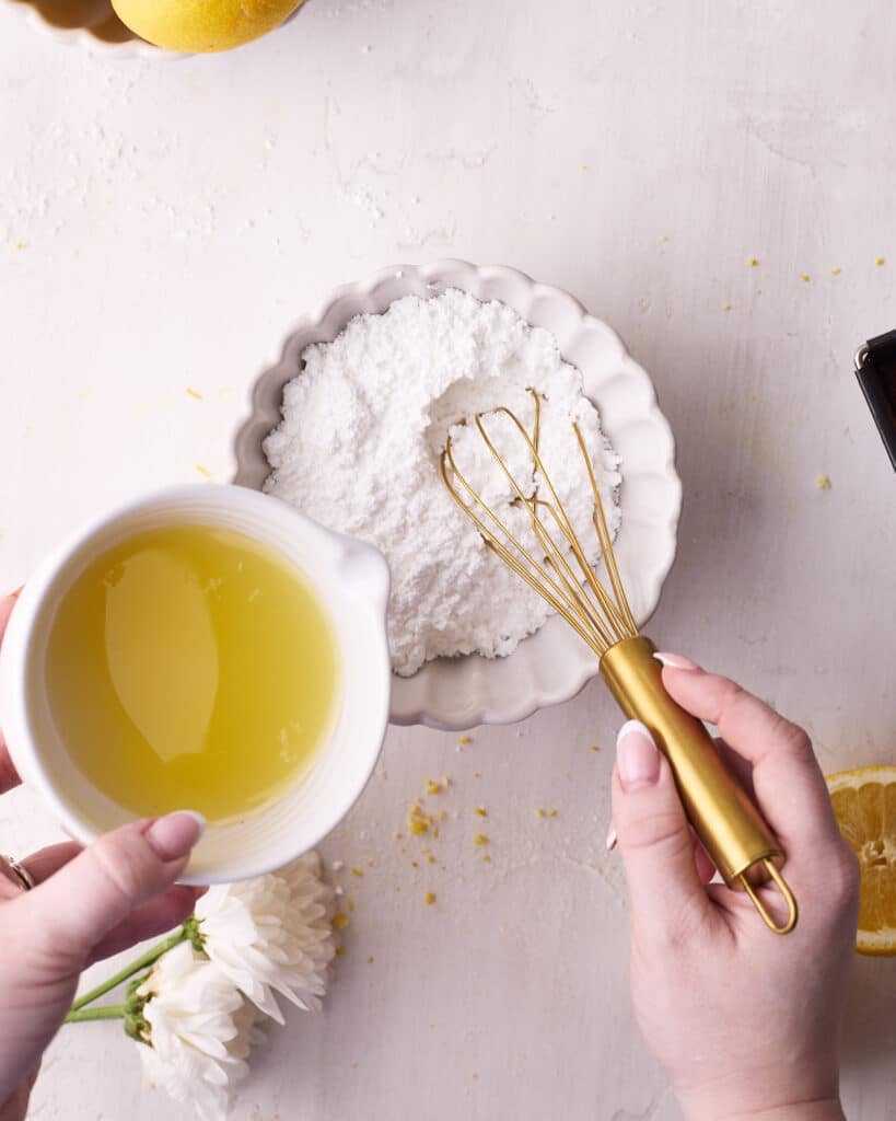 Adding squeezed lemon juice to powdered sugar to make lemon glaze for lemon cake. 