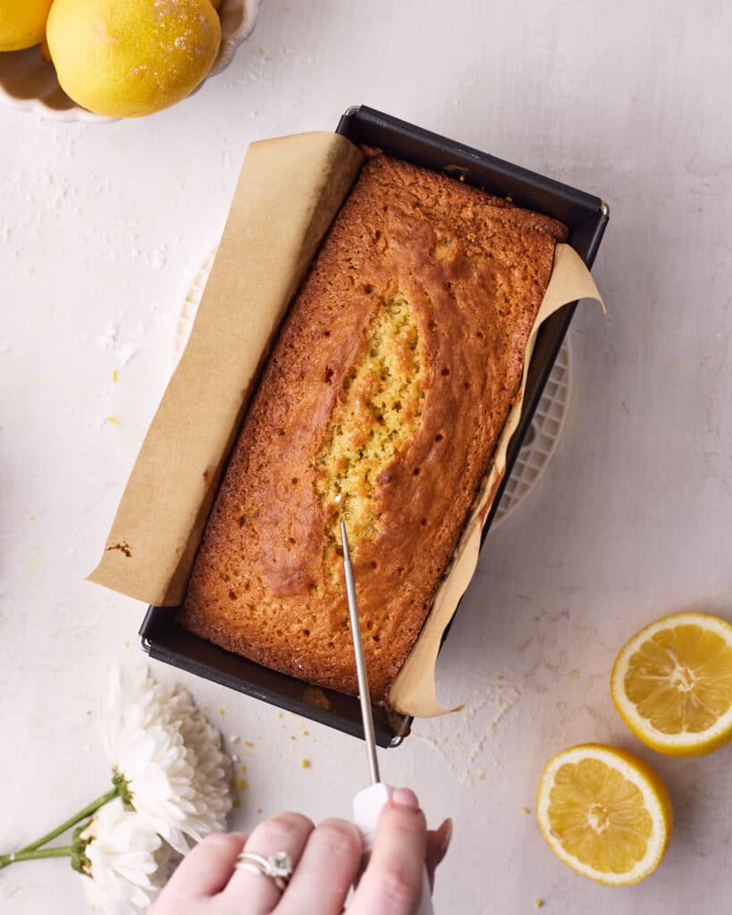 Lemon cake with holes pricked all over it with a skewer to make lemon drizzle cake.