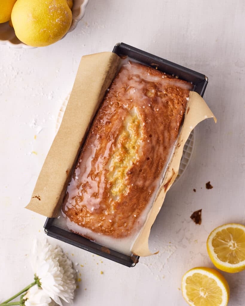 Warm lemon cake that has just had lemon glaze poured over it.