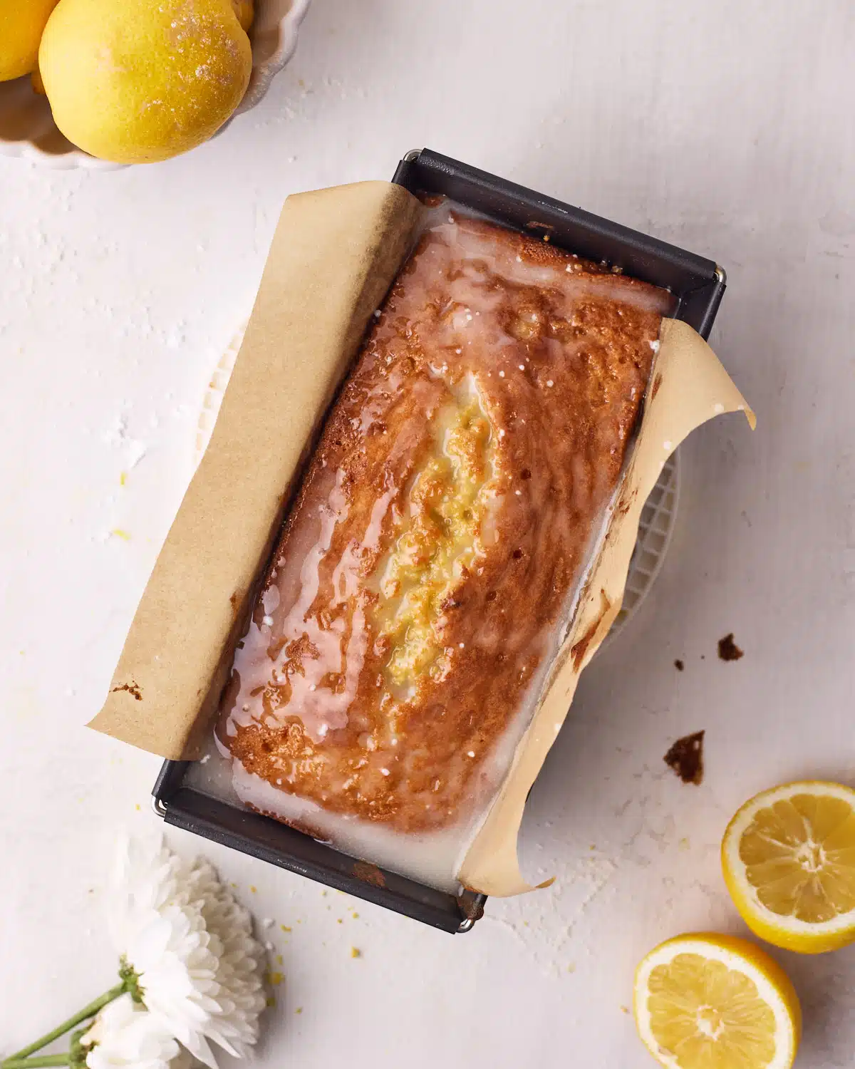Warm lemon drizzle cake that has just had lemon glaze poured over it. 